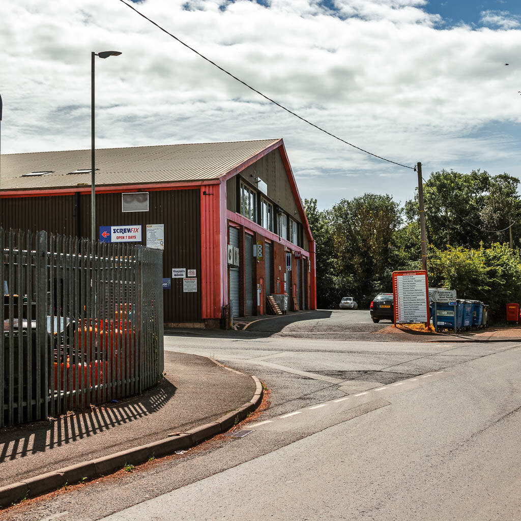 the road, with a warehouse building on the left.