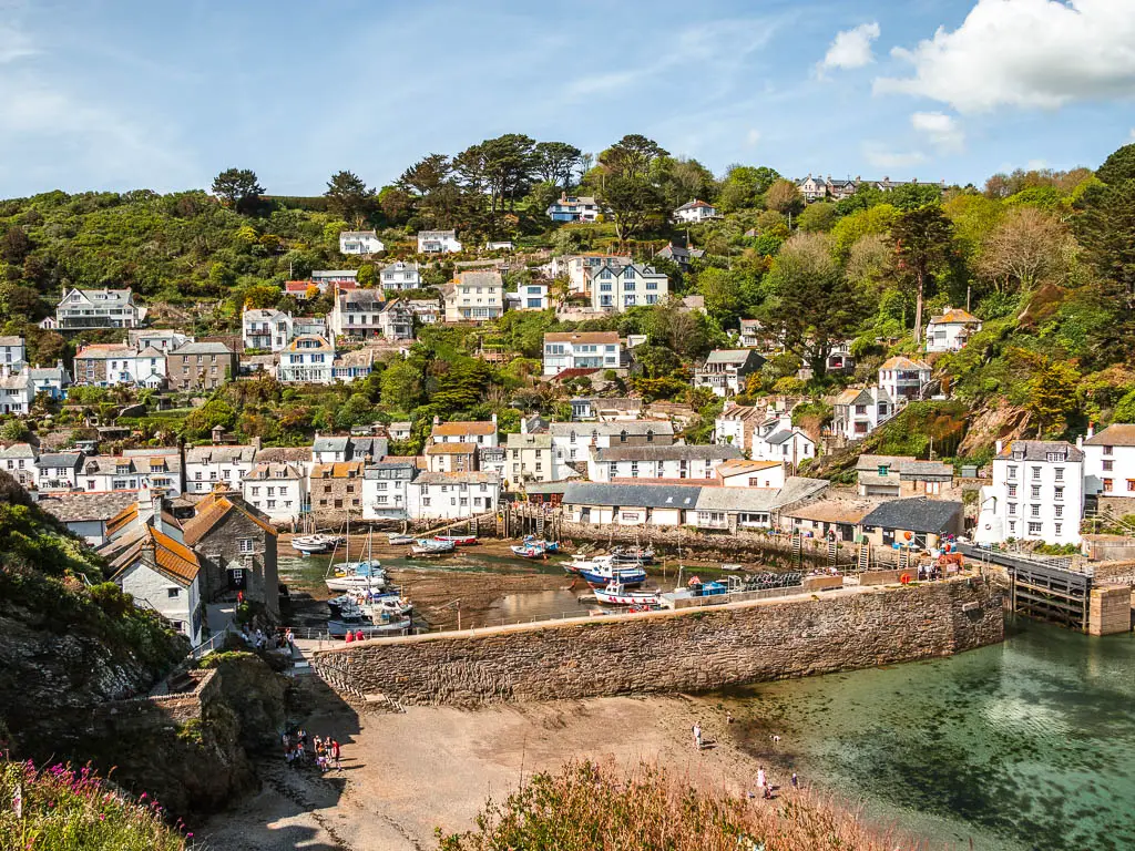 Looking down into Polperro at the end of the walk from Fowey. There is a small beach then a sea wall, with the harbour behind that then lots of houses running up the hill on the other side.