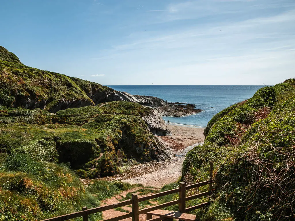 Looking through the cliff opening to the sandy beach and blue sea.