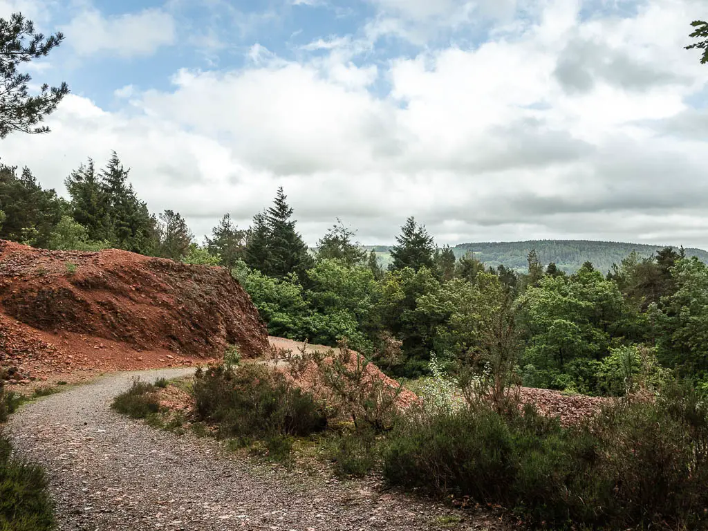 A trail snaking around the hill, with a view across the tree tops ahead.