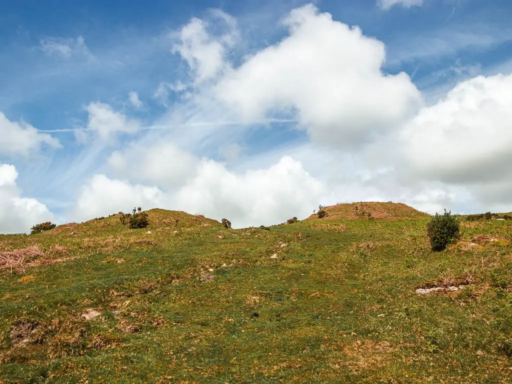 Looking up a grass covered hill with two small quarry hills at the top on the walk up to the Redlake Tramway. 