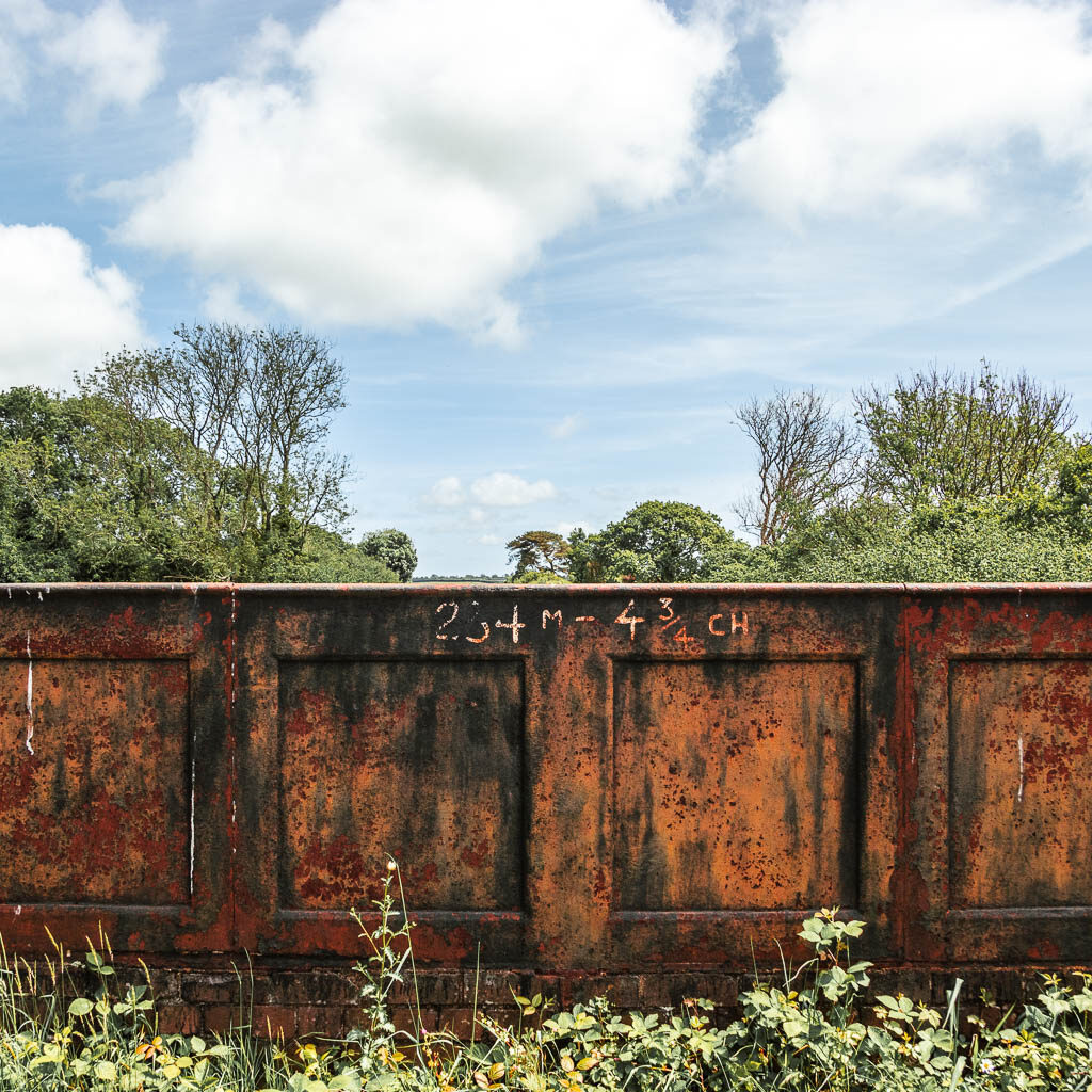 A metal wall, with some tree tops visible on the other side.