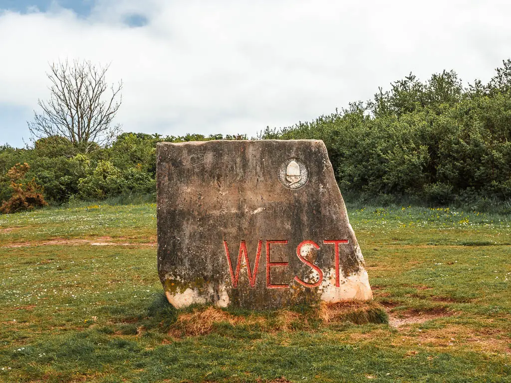 A large stone sign with an acorn and the word 'WEST' in red.