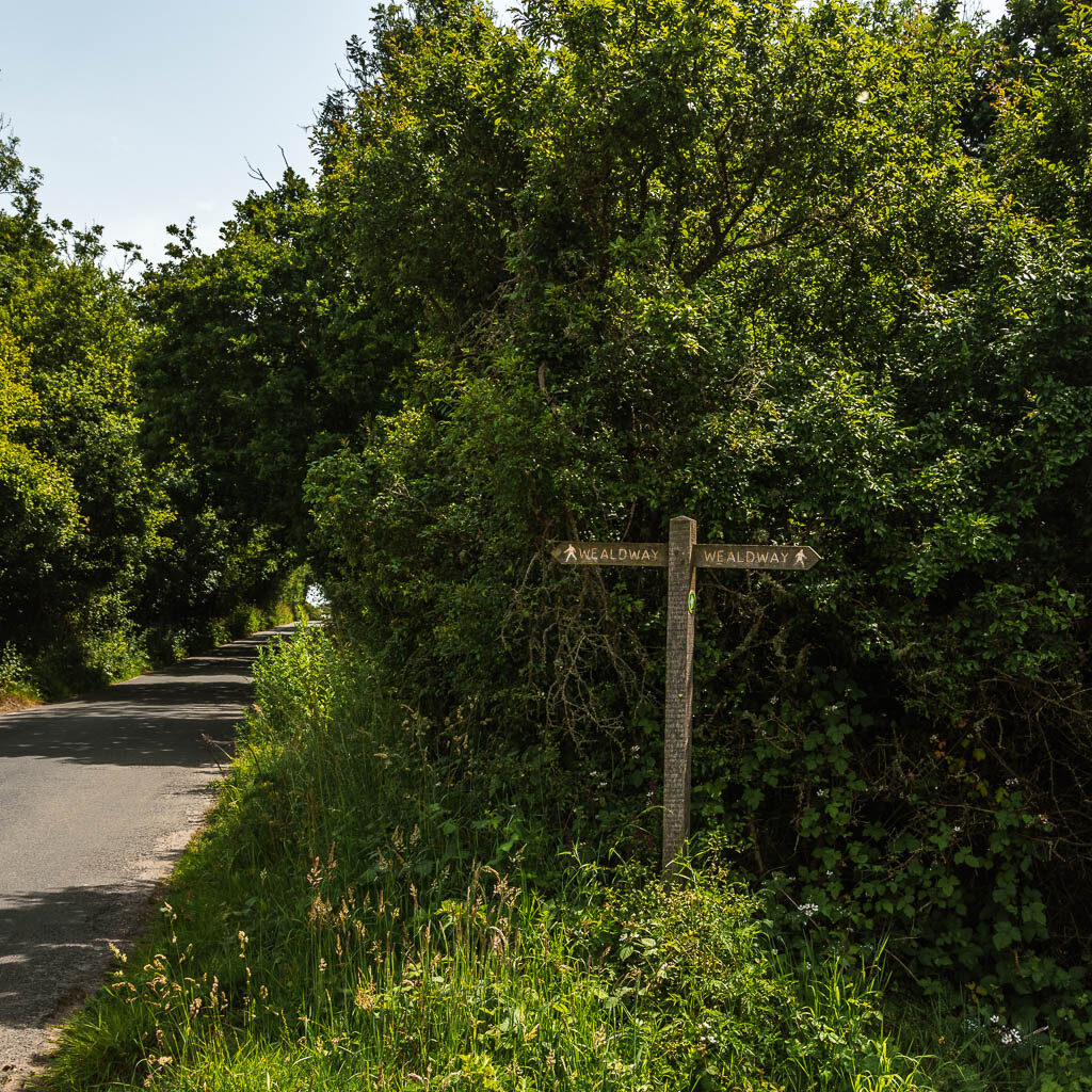 A cross trail signpost on the side of the road.