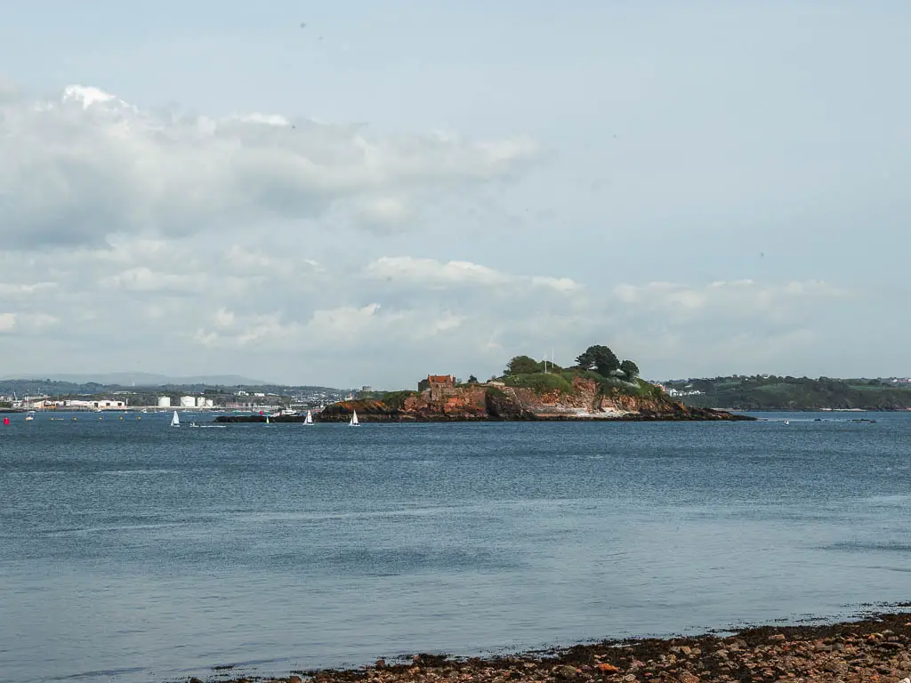 Looking across the calm blue sea to Drakes Island at the start of the Mount Edgcumbe to Kingsand circular walk.