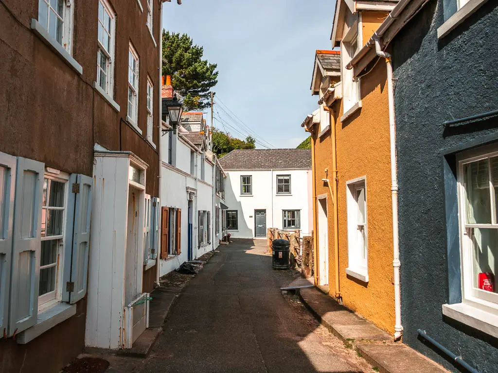 Looking down a small road lines with pastel coloured houses in Kingsand. 