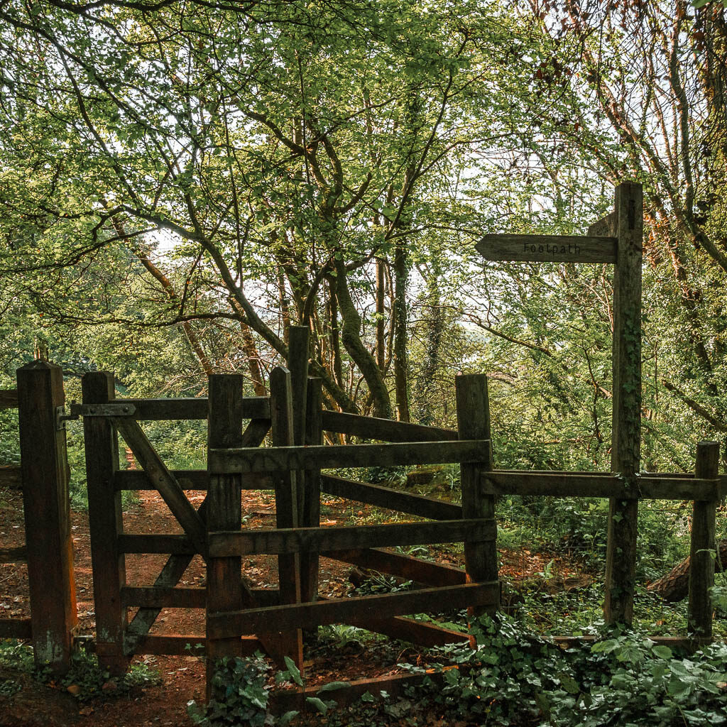 a wooden gate with a wooden trail signpost.