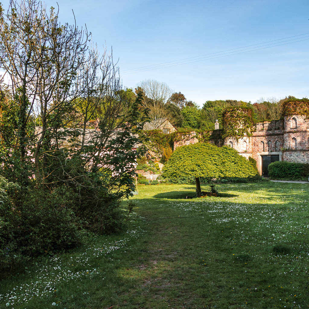 Looking along the neatly cute grass to a castle type building ahead covered in ivy on the Mount Edgcumbe to Kingsand circular walk.