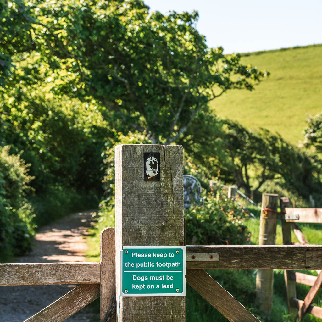 A wooden gate with a red and white acorn sign on it.