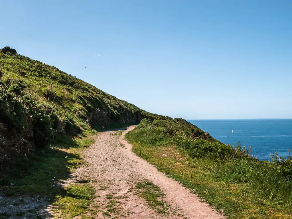A wide gravel path along the side of the grass hill.