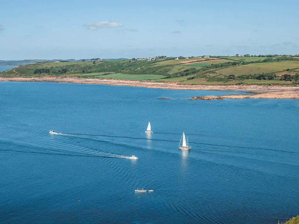 Looking down to the blue sea with a few white sailing boats, on the walk from Noss Mayo, near Plymouth.