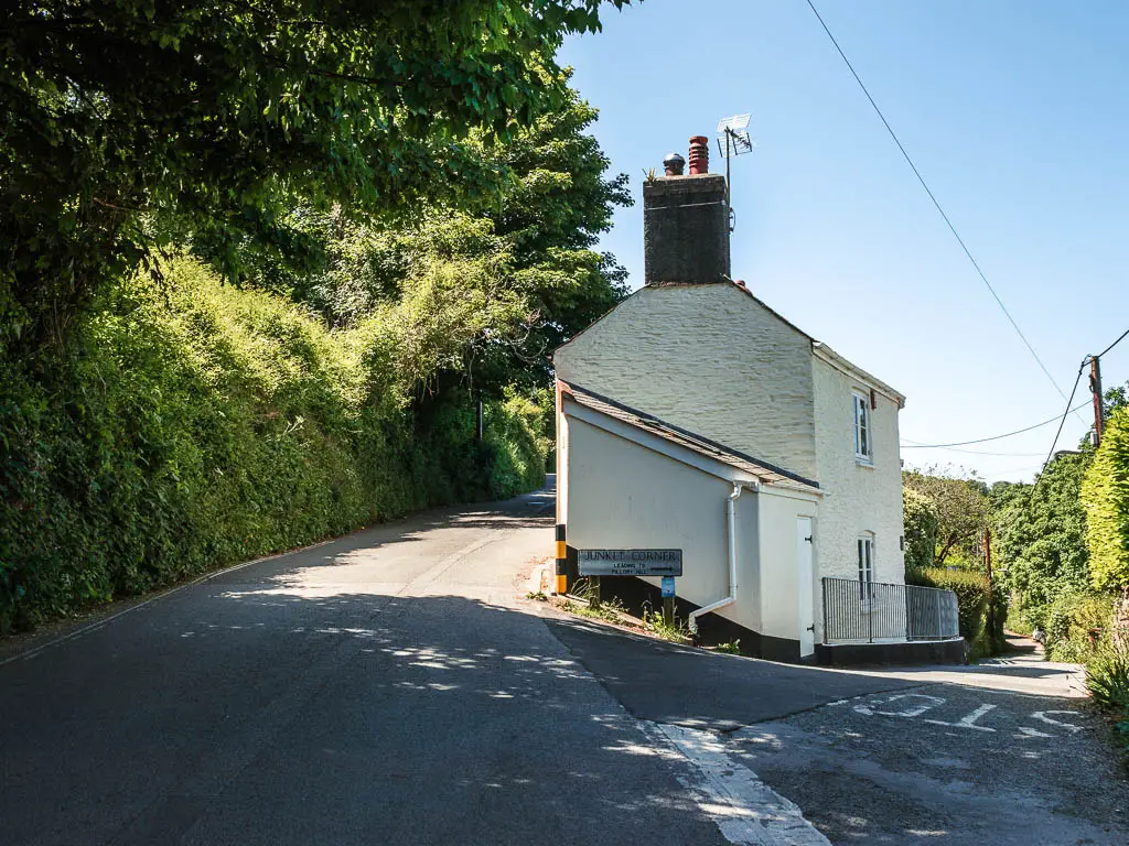 A road split, with a white coloured stone house in the middle.