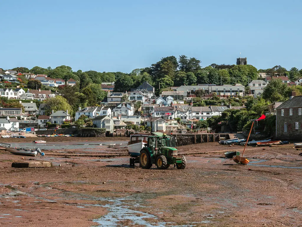 A tractor on the river bed at low tide on Noss Mayo, at the start of the coastal walk. There are village houses on the other side of the river bed.