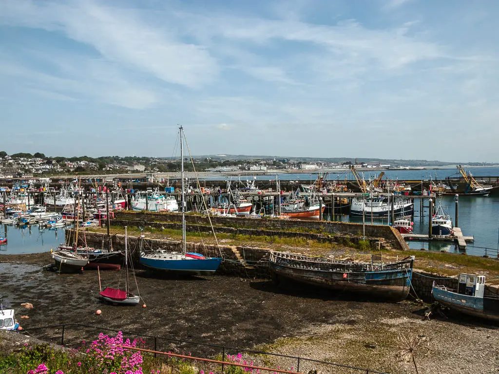 Looking across the harbour at low tide on the walk from Penzance to Mousehole. there are large and small boats resting on the sea bed.