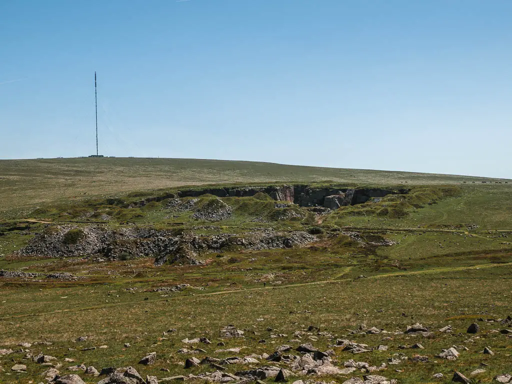 Looking across the moor to the top of a hollowed out hill in the distance.