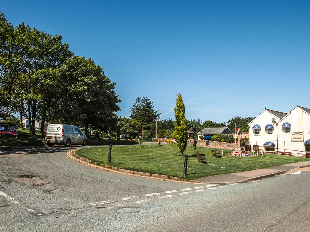 Looking across the main road to a side road looping around a green island.