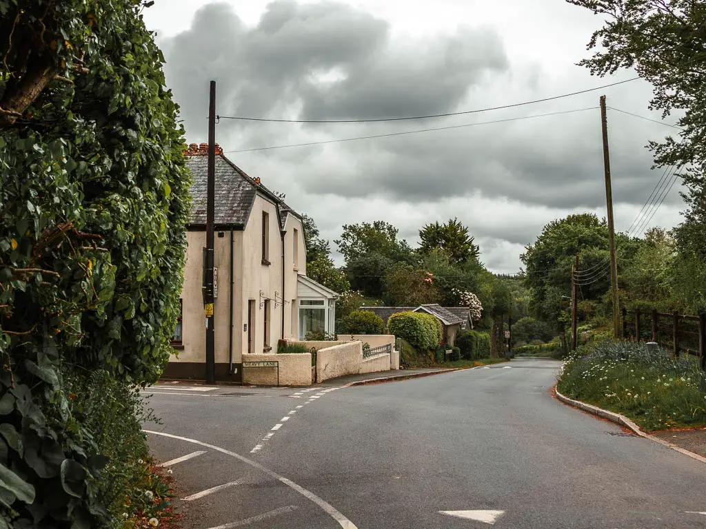 A road leading straight, with a side road to the left and a house on the corner.