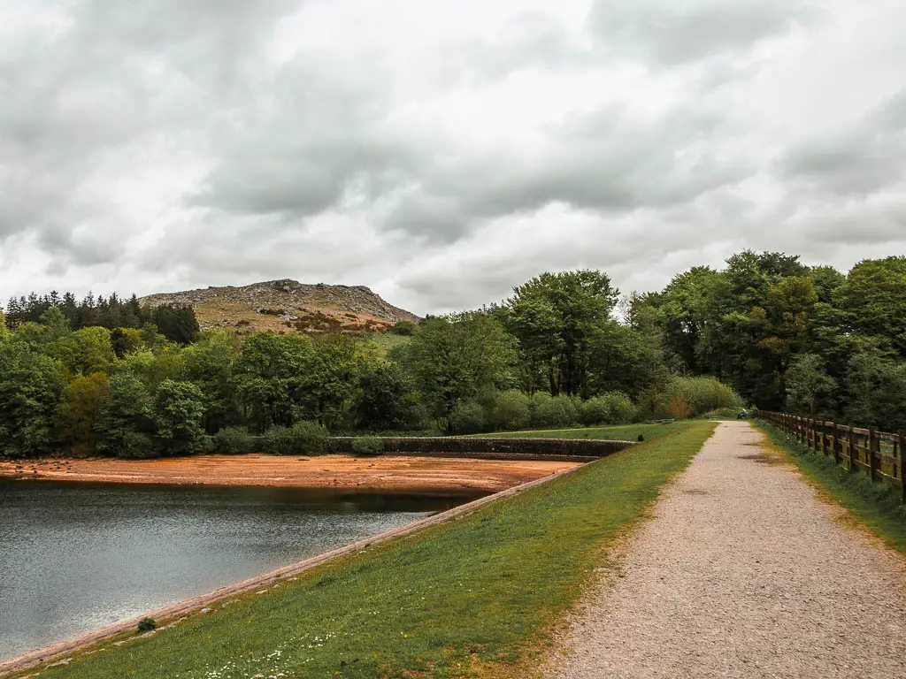 A wide path on the right, with a grass bank to the left leading to the reservoir, and Sheepstor visible ahead on the distance, part way through the circular walk.