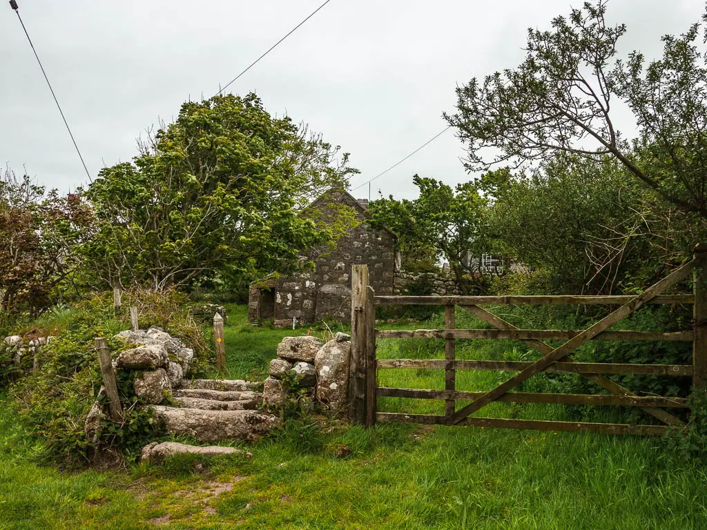 Stone steps, with a wooden gate to the right, and a stone shed on the other side. 