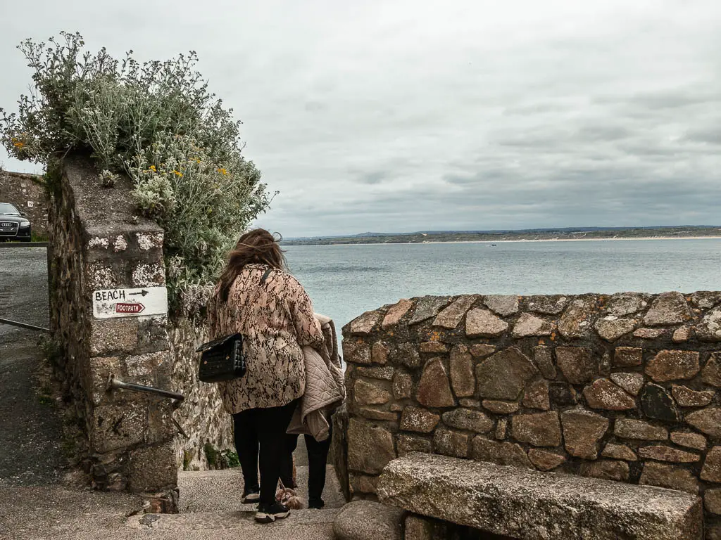 A gap between the stone walls, with people walking through it. 