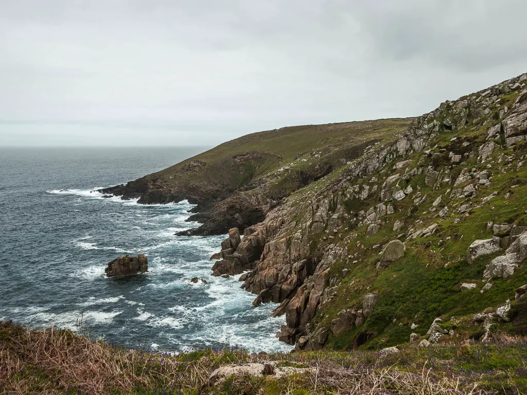 The cliffs sloping down to the sea and covered in grass and rocks, then turnings to rocks at the bottom on the coastal walk from St Ives to Zennor.