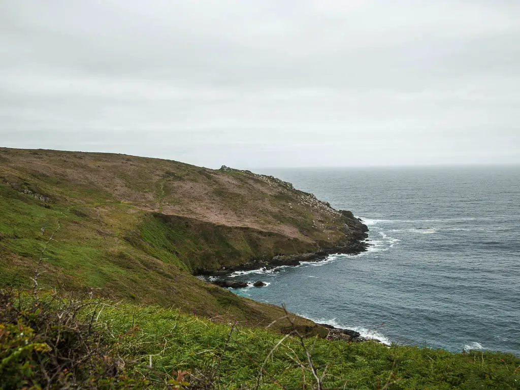 Looking down and along the grass covered underling cliffs toward Zennor Head on the coastal walk from St Ives. There is a barely visible trail running across the side of the cliff.