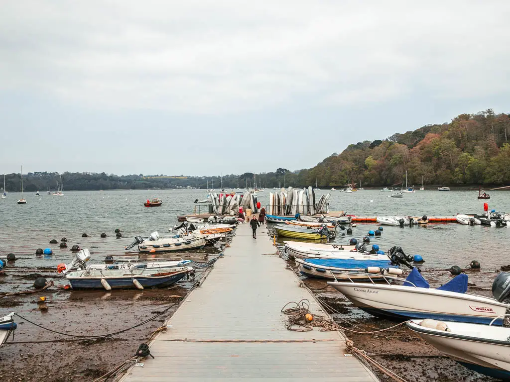 A pier lined with lots of small boats, leading into the river.