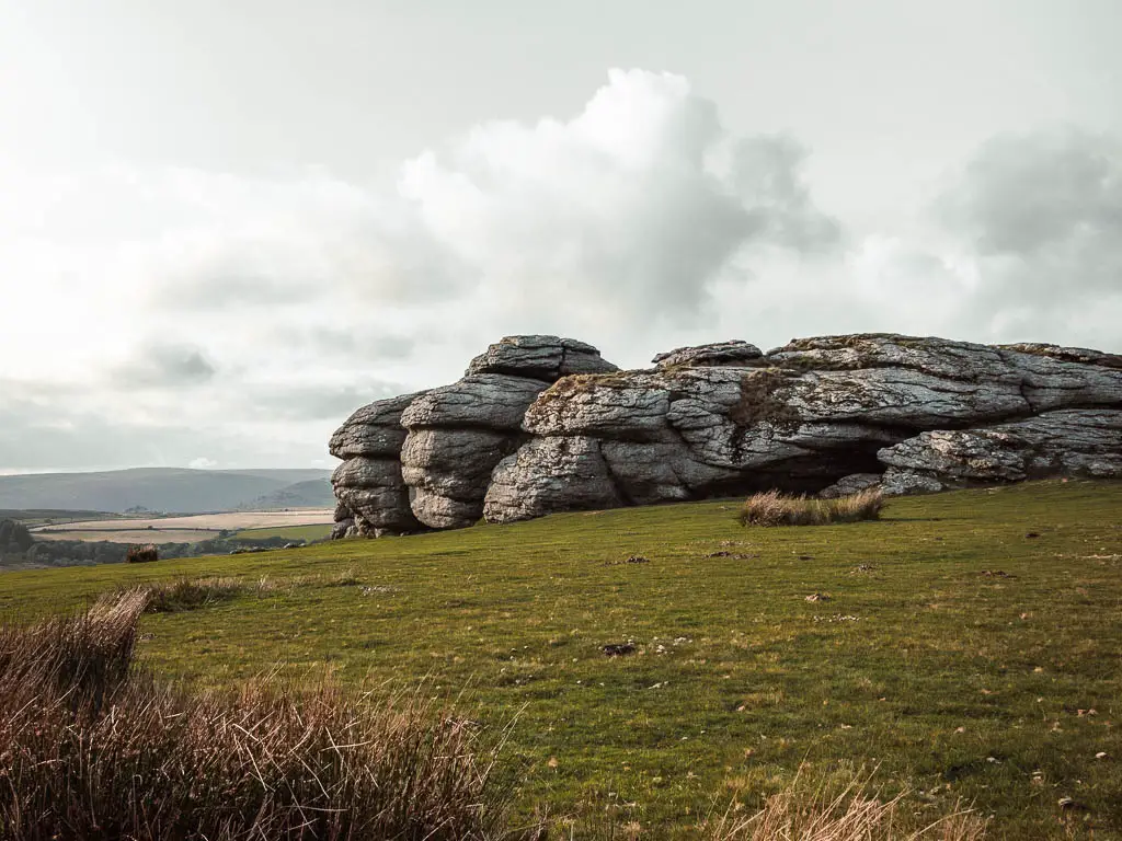 A large tor surround by green grass.