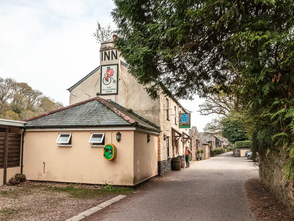 The Maltsters inn on the side of the road. There is a person standing at the entrance. 