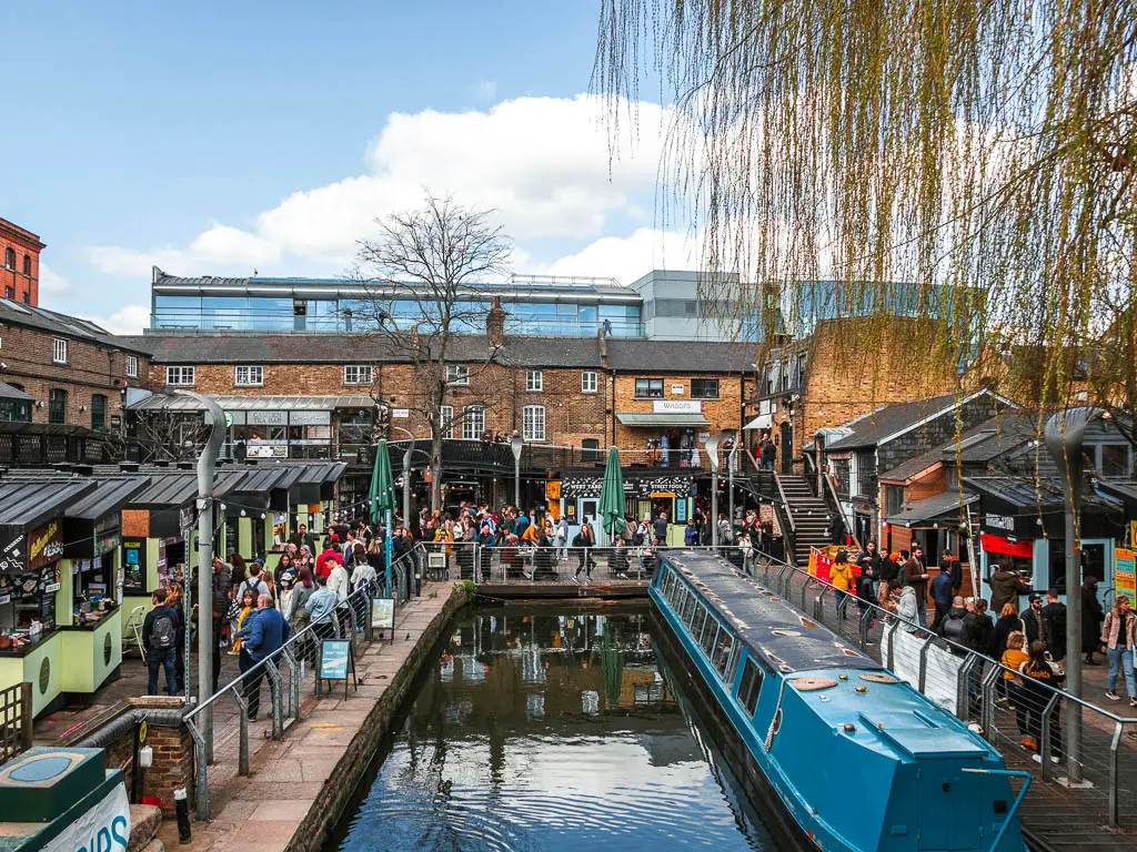 Looking down to Camden market with lots of food stools, lots of people and a blue barge.