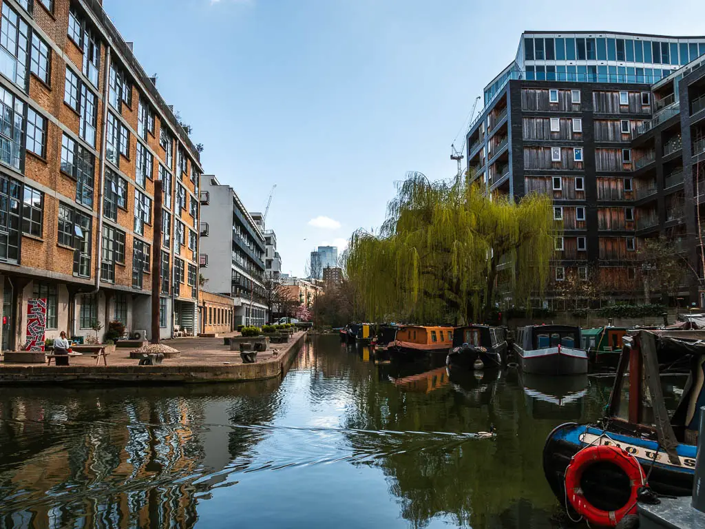 A branch of the canal, lines with apartment blocks, and there are some barges moored under an overhanging tree.