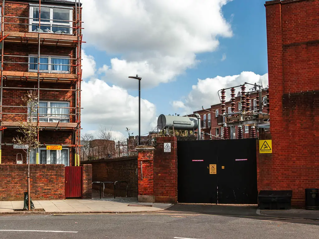 A road corner, with red Brock buildings and a small walkway gap between the buildings. 