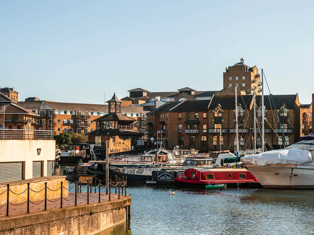 Limehouse basin with a bunch of barges moored, and brown brick buildings on the other side.