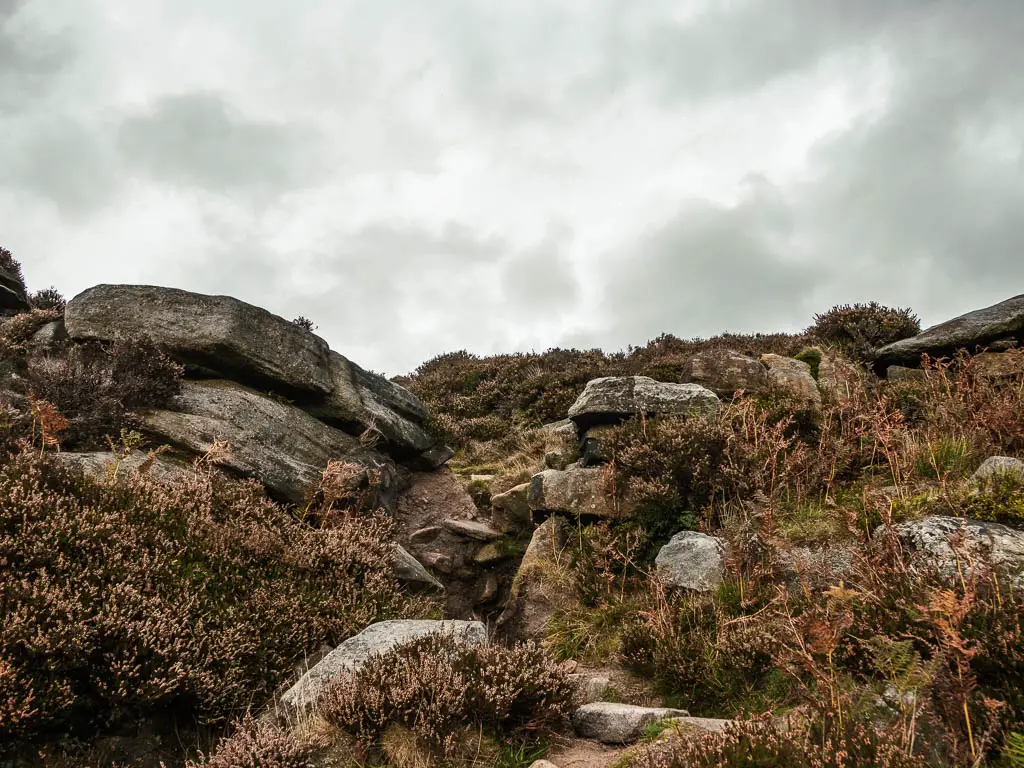 A barely visible dirt trail leading up through big boulders.