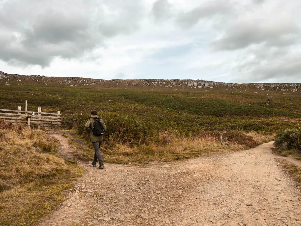 A trail split, with a man walking along the left trail.