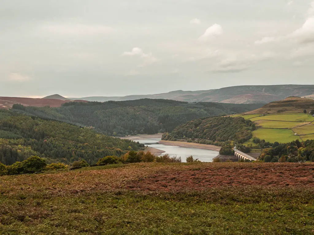 Looking down the hill to the valley and the Ladybower Reservoir. The reservoir is surround by hills with lots of trees.