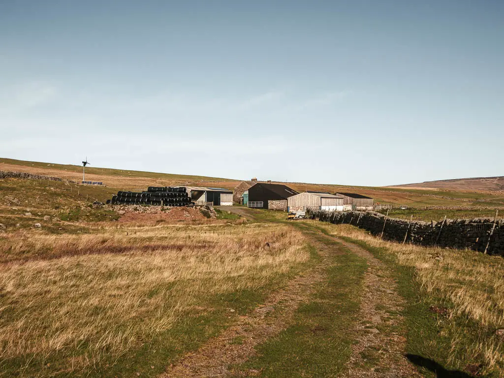 A trail track leading to farm buildings.