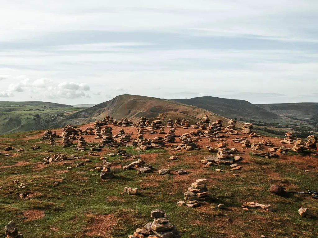 Lots of little stacks of stones on the top of Back Tor, with some hills in the distance.
