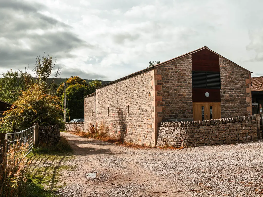 A large brick barn type building surround by gravel road.