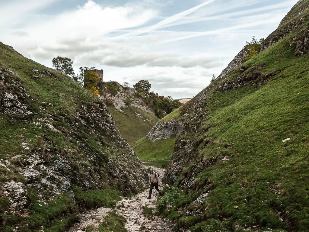 A man walking along a rocky path, between the stone cliff walls, through the valley of Cave Dale.