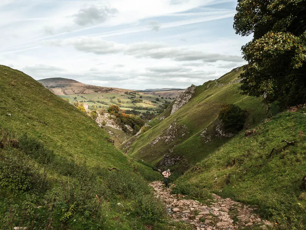 A man walking along a rocky path through the valley of Cave Dale.