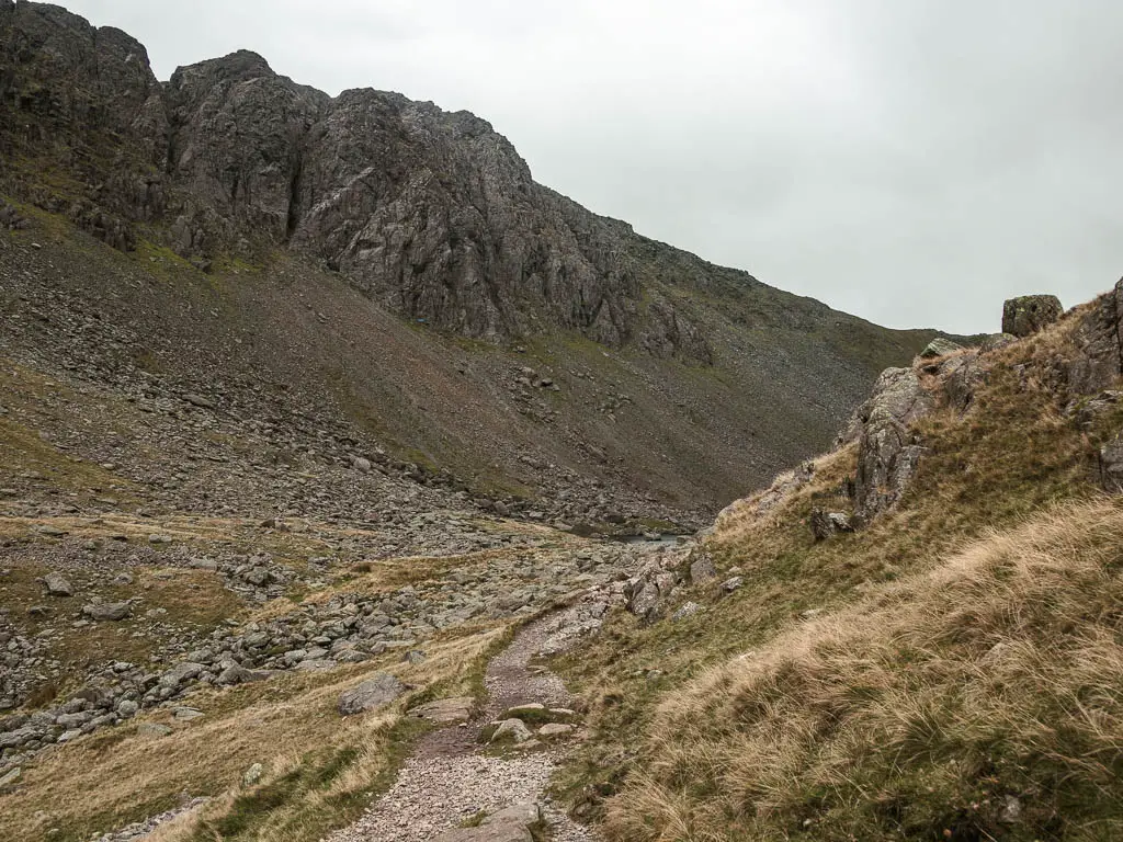 A narrow stoney path leading into a valley between the fells.