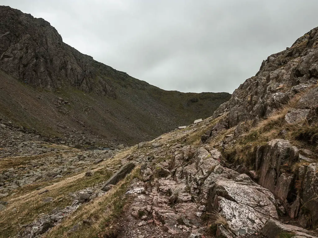 A rocky path leading into the valley, with a big hill ahead.