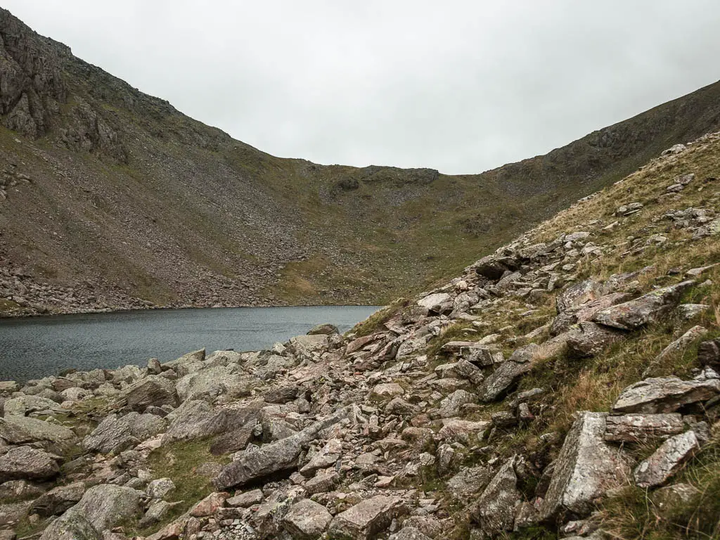 A rocky path, with a body of water called Goats water to the left, with a big hill surrounding it.