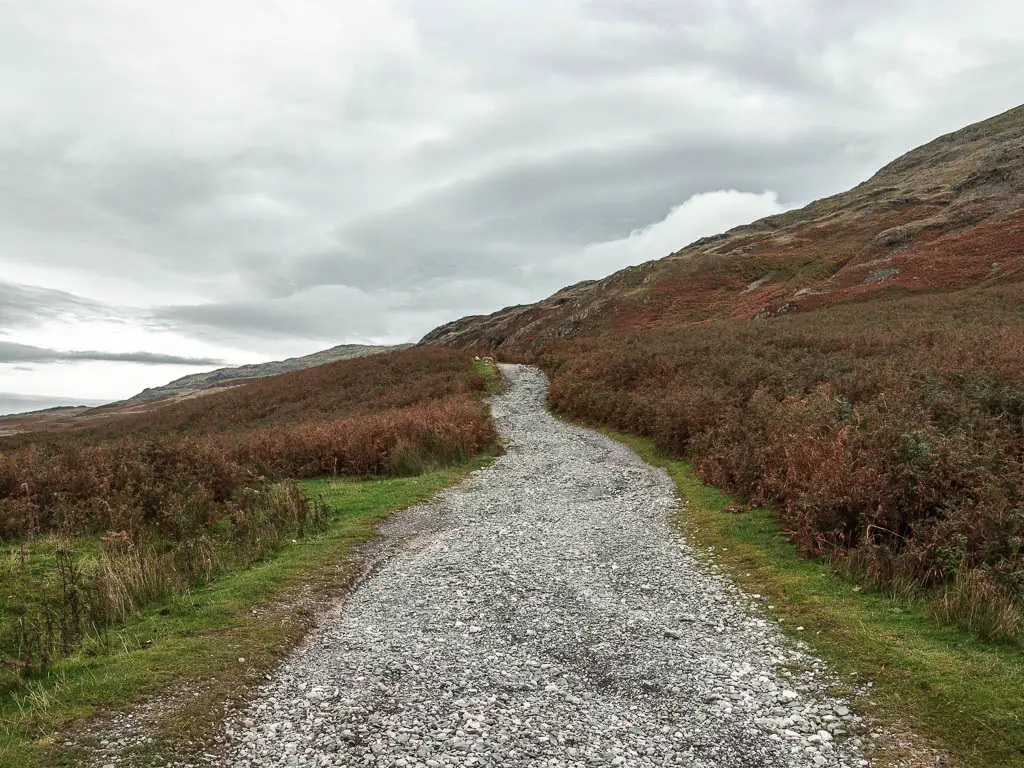 A gravel path running straight ahead, with a hill on the right side.