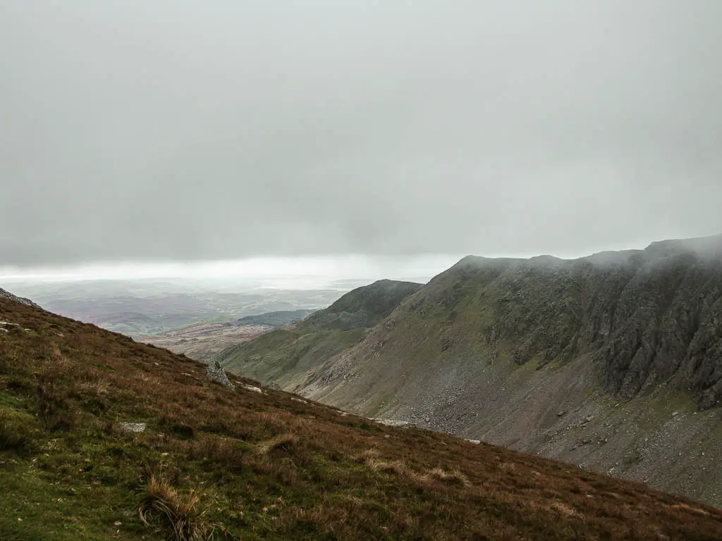 Looking down the hill side into the valley, with the sky filled with fog and mist.