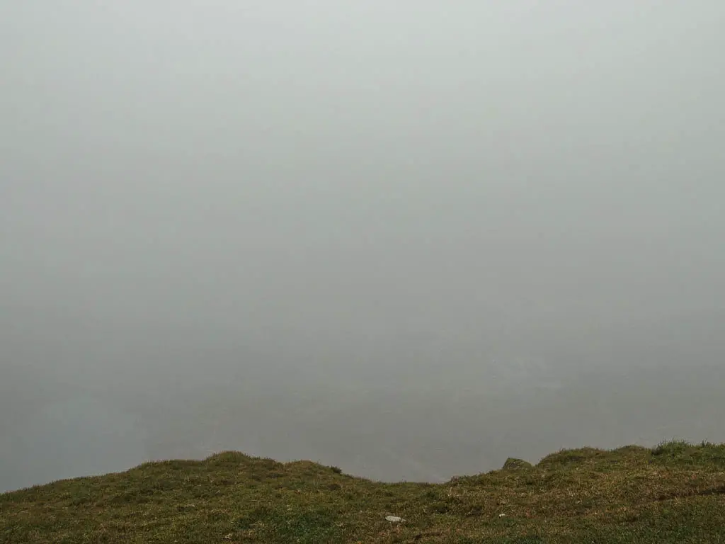 Looking down the hill top a view of grey mist and fog.