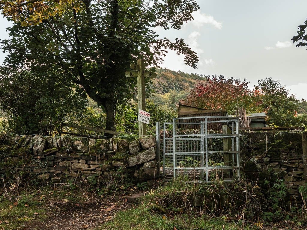 A metal gate and wooden signpost in a stone wall.