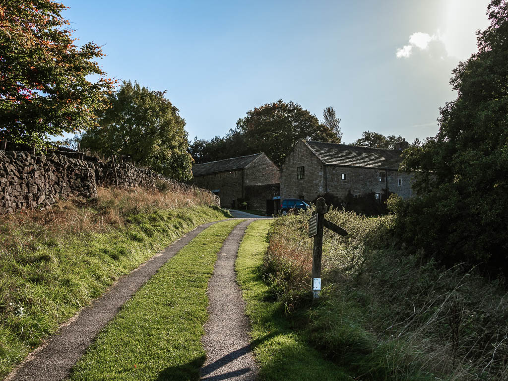 A road track leading to some grey houses.