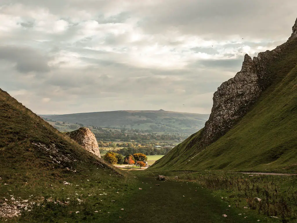 Looking through the grass covered gorge. At the end of the gorge the light is shining down onto the fields.